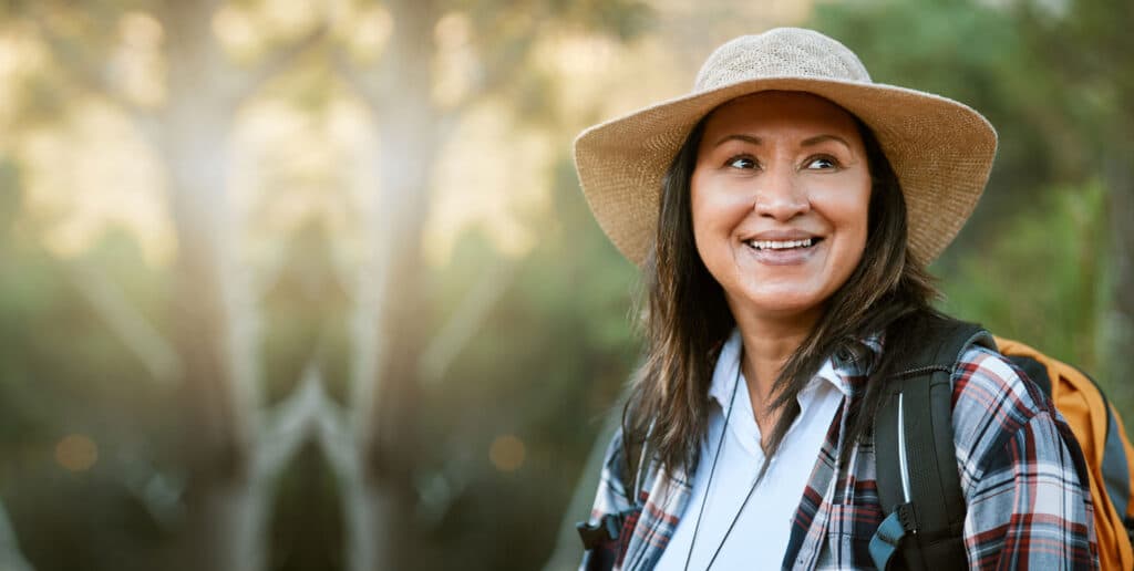 Mature Native American woman wearing a wide brimmed hat outdoors while hiking